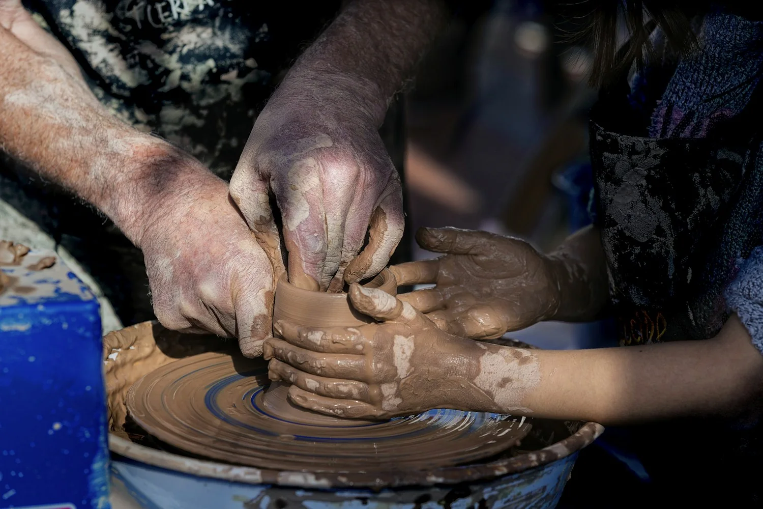 Hands carefully shaping a vessel on a pottery wheel