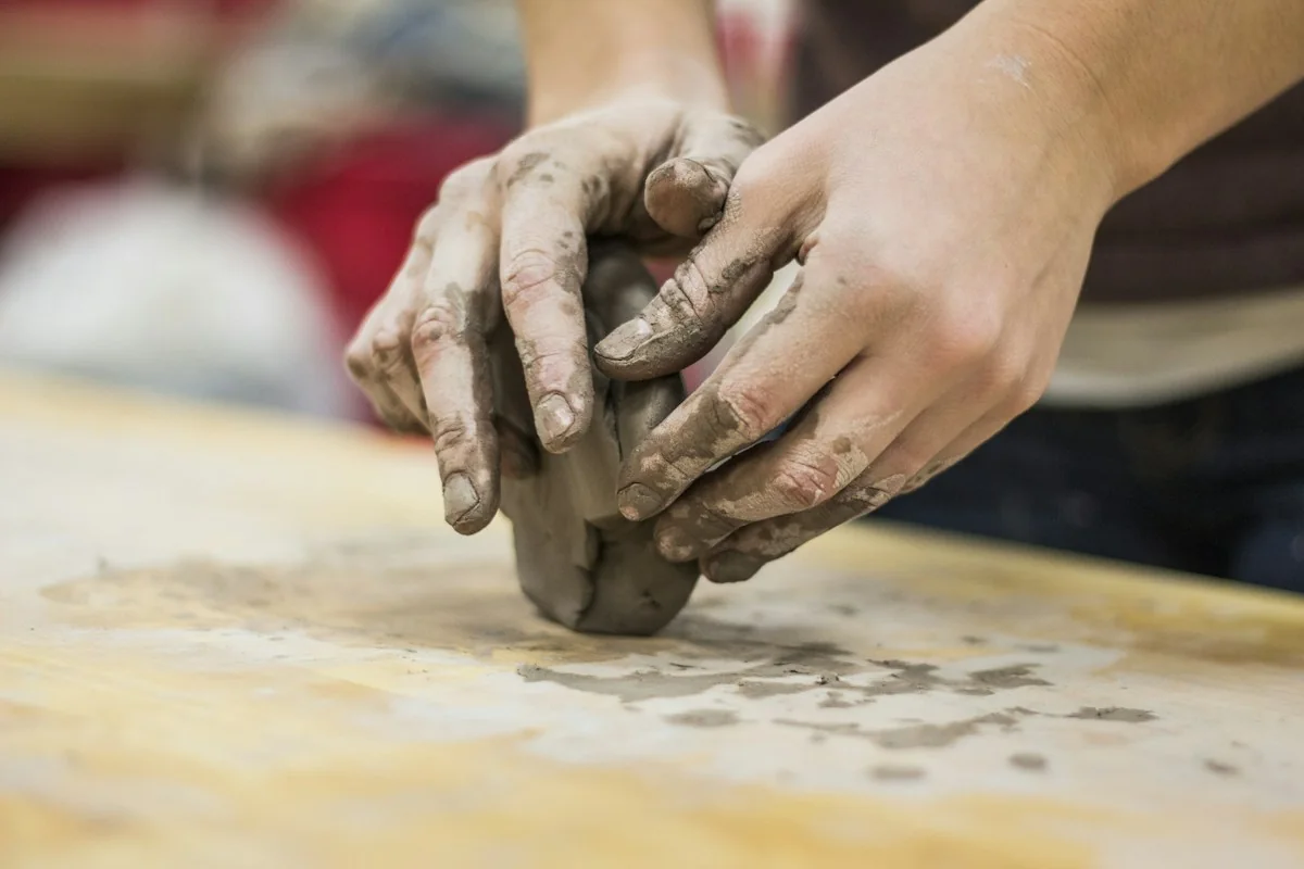 Clay-covered hands working directly with the material
