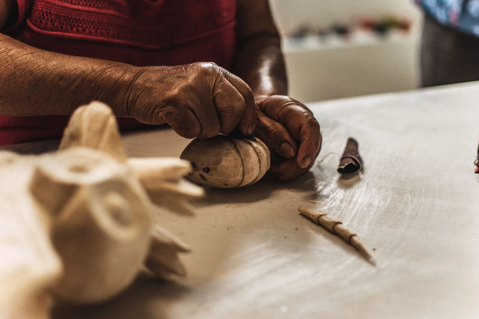 An artisan carving a wooden form with a small hand tool
